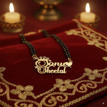 Gold necklace with 'Sonu Sheetal' engraving on a red embroidered fabric background with candles.